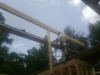 Carpenter setting a ridge beam over a new addition frame — Ice Dam Removal by Roofing Brothers in Crescent Mills