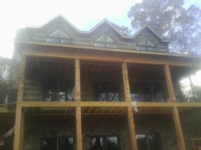 Dormers and porch framing on a large log home under construction — Roof Coating work by our crew in Crescent Mills